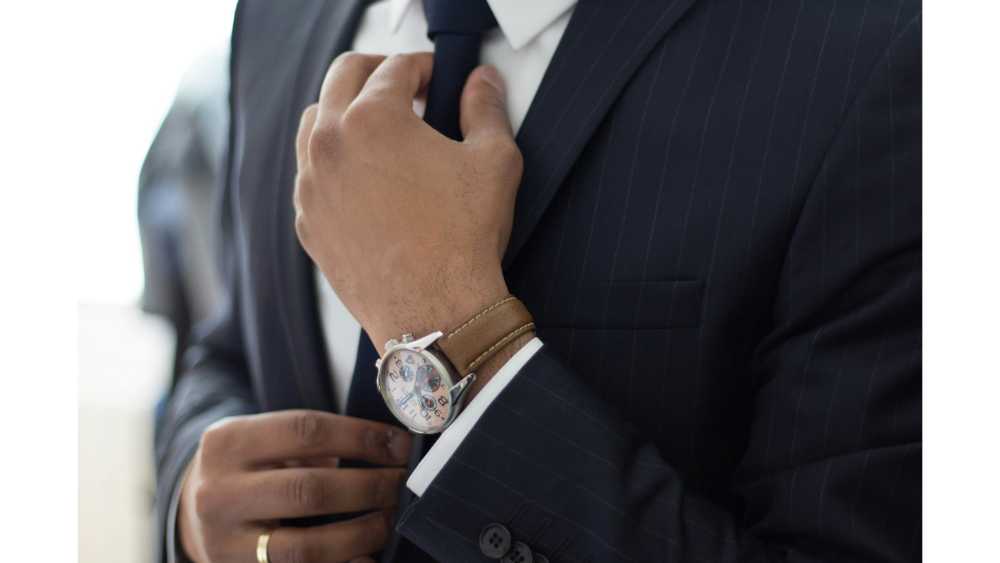 Businessman adjusting his tie while wearing a suit and wristwatch