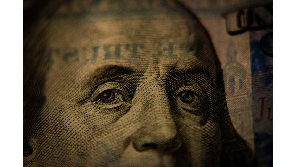 Extreme close-up of Benjamin Franklin’s eyes from a U.S. one hundred dollar bill, emphasizing detail and currency security features.