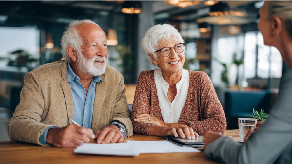 Senior couple sitting at a table, smiling and engaging in a financial consultation with an advisor