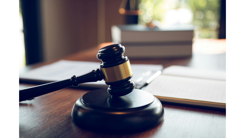 Wooden gavel on a desk beside legal paperwork and books in a softly lit office