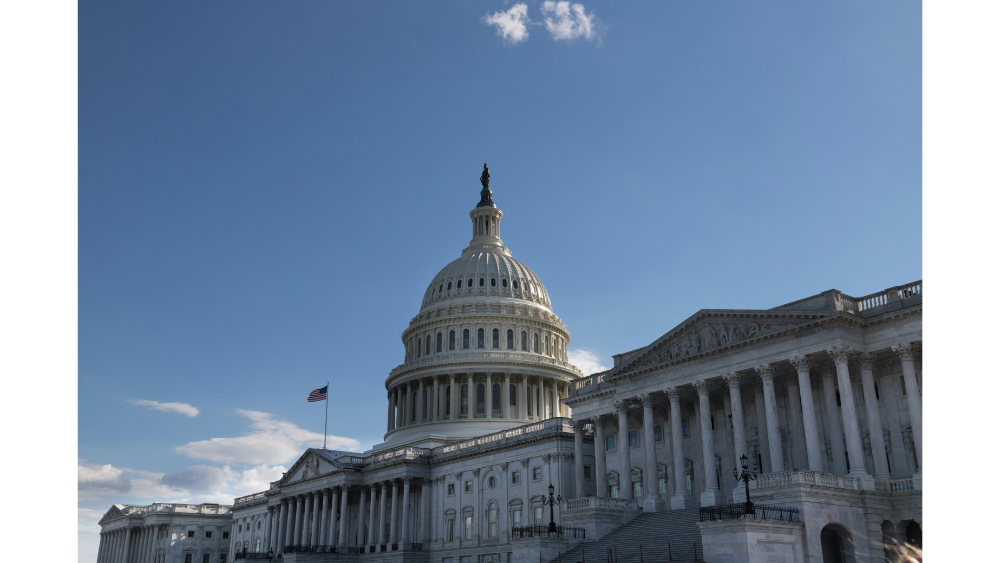 Exterior view of the United States Capitol building on a clear day with an American flag flying.